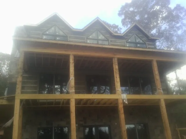Dormers and porch framing on a large log home under construction — Roof Coating work by our crew in Pierce